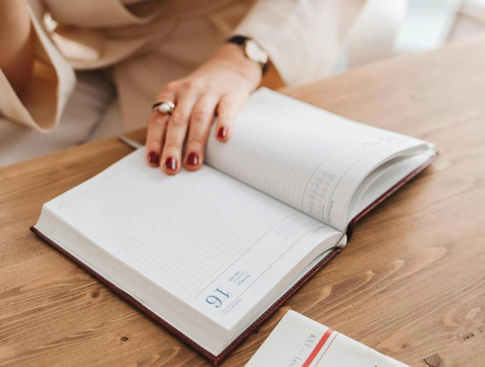 Person writing in a notebook beside a KS3 literacy book